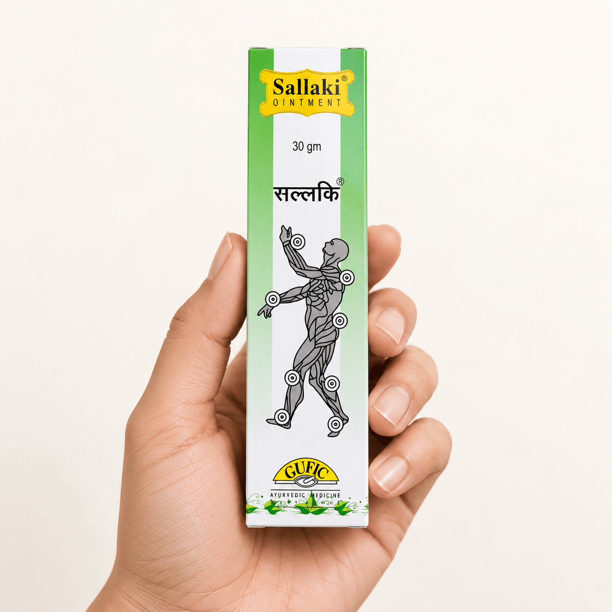 Hand hält die grün-weiße Verpackung der Gufic Sallaki Weihrauchsalbe 30 g